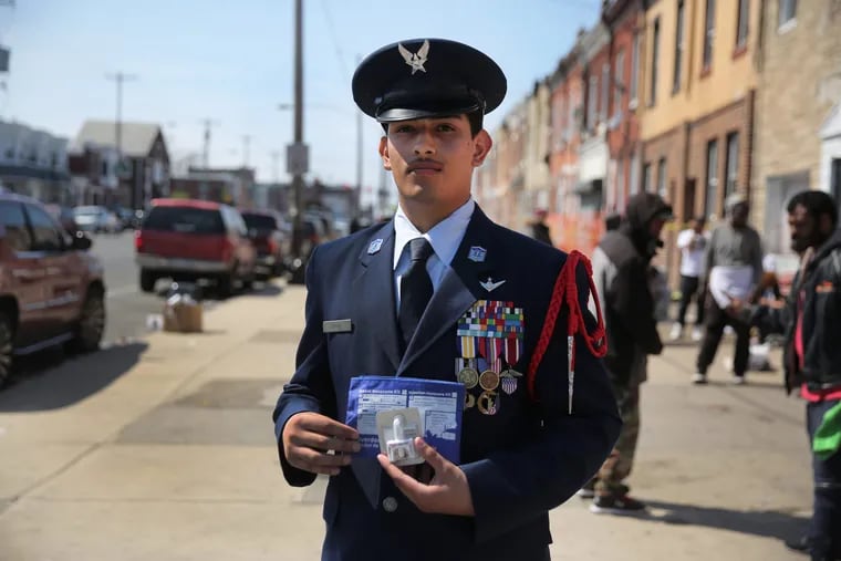 William Cruz,17, dressed in his junior ROTC uniform, holds Narcan nasal spray at the corner of G Street and Allegheny Avenue. He used the spray to save the life of an overdose victim.