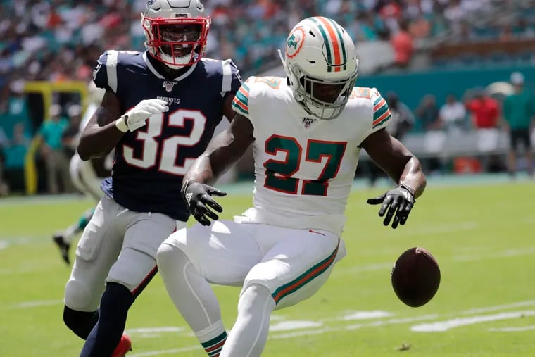 Dolphins running back Kalen Ballage drops a pass under pressure from Patriots safety Devin McCourty during the first half on Sunday.