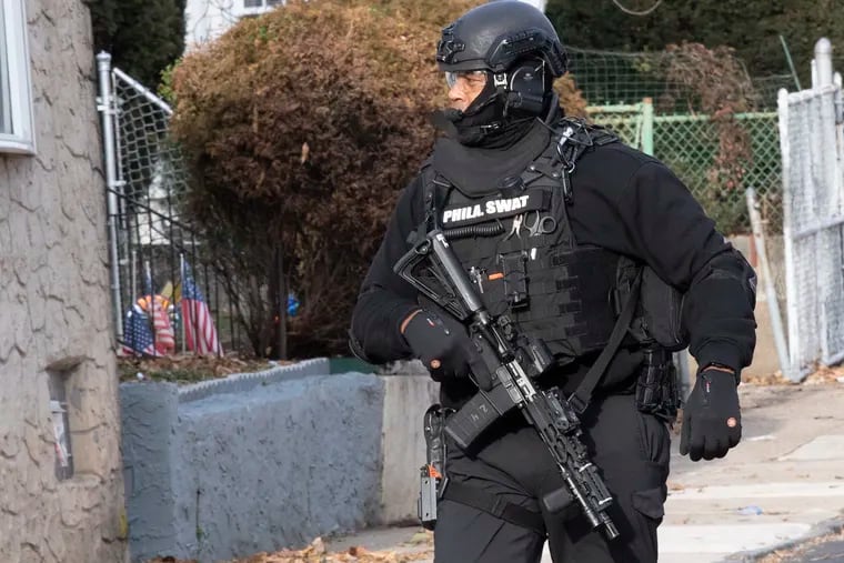 A Philadelphia SWAT team member secures the area where a man being served with an arrest warrant opened fire on officers Thursday on the 4600 block of Hawthorne Street in Frankford.