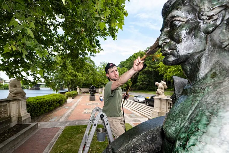Art conservator Zach Tatti adds a layer of protective wax to "Spanning the Continent," a sculpture along Kelly Drive. Tatti's family company has been cleaning and tending to nearly 40 of the city's public sculptures for decades.