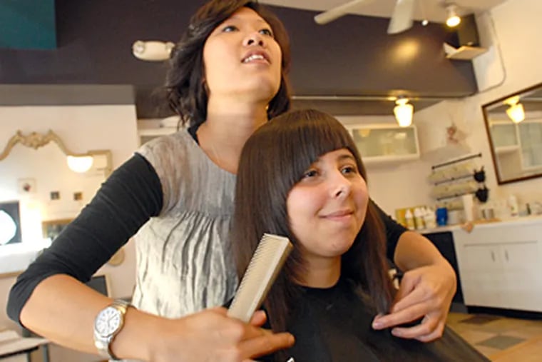 At Plume salon in Fishtown,stylist Jenni Nguyen checks Janine Wheatley's hair. Janine's new style features bangs. (April Saul / Staff)