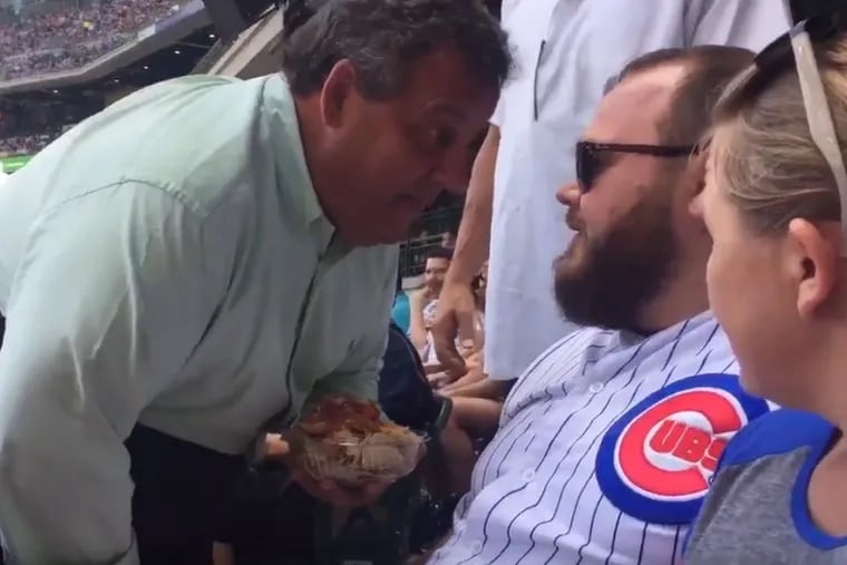 New Jersey Gov. Chris Christie taunts Cubs fan Sunday in Milwaukee while clutching a plastic container of nachos.