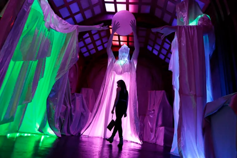 A woman walks in “The Warehouse” at the VIP preview of Otherworld, an art installation at 2500 Grant Ave. in Philadelphia, on Aug. 3.  Otherworld, an immersive experience spanning 55 rooms and 40,000 square feet, takes visitors on a trippy journey as they enter a lifetime subscription to be a part of a futuristic community centered around a HAL 9000-like computer.