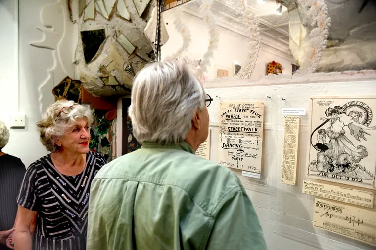 Julia Zagar (left) co-owner of Eye's Gallery and architect, artist, author, and community activist Joel Spivak (right) look over an exhibit of the South Street Renaissance, upstairs in her store in the 400 block of South Street. Spivak is also co-founder of the found-object artists known as the Dumpster Divers. The bohemians and hippies of the South Street Renaissance will soon be celebrating a 50 year reunion.