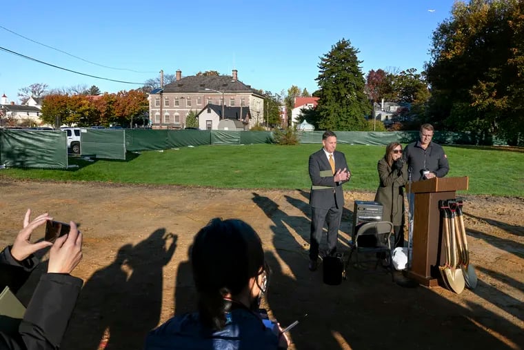 Haddonfield mayor Colleen Bianco Bezich (center) speaks during groundbreaking Thursday for The Place at Haddonfield, a long-delayed complex of affordable rental townhouses to be built behind Borough Hall (rear). With her are commissioners Kevin Roche (left) and Frank Troy (right).