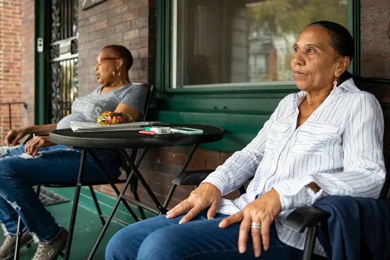 Regina Jones, 66, right, and Bernadine Mills, 67, sit on Mills' porch on the 5000 block of Walton Avenue where a quadruple slaying took place the night before.