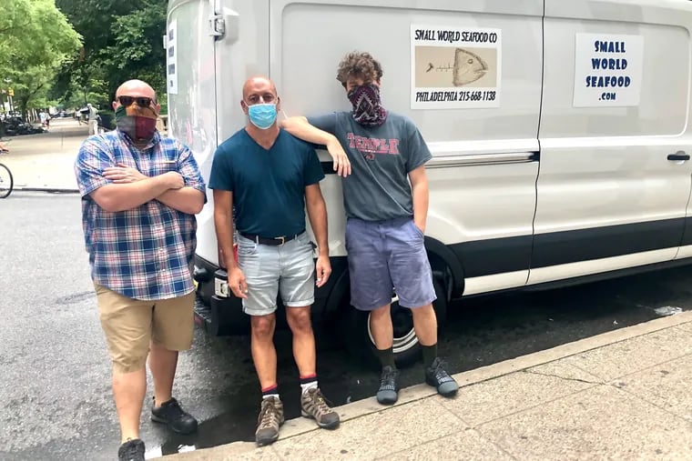 Small World Seafood partners Andy Farrell (left) and Robert Amar (center), with employee Matthew Lotkowski, pause beside the delivery truck at one of their weekly Friday drop-offs in front of the Ethical Society on Rittenhouse Square.