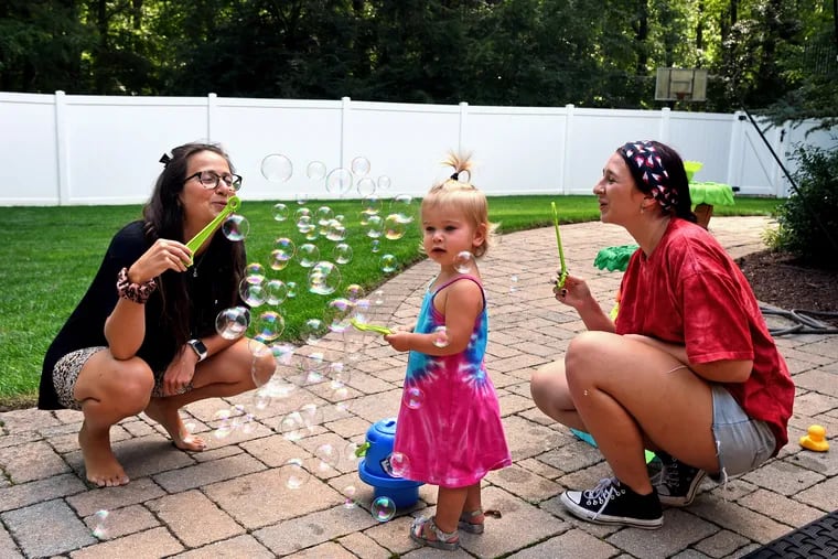 Gabi Zucker (left) and her 17-month-old daughter, Mikaela, with caregiver Dani Deal, 21, at the Zuckers' Cherry Hill home on Aug. 20, 2020. Zucker is enrolled in the JHEART program sponsored by the Cherry Hill JCC, which arranges for babysitters to provide care for young children, one of the alternate programs that are popping up across the region for parents.