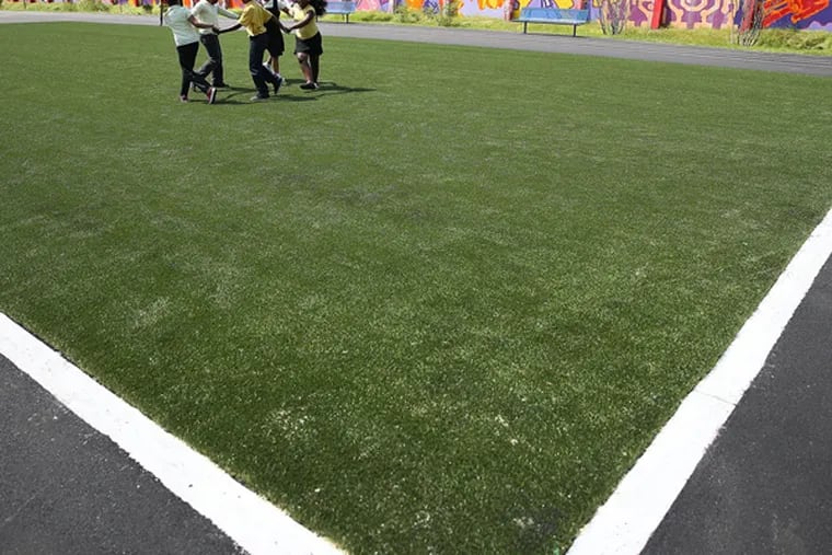 Students from the William Dick School play on the new artificial turf field on the school's playground in North Philadelphia on June 3, 2014. (DAVID MAIALETTI / Staff Photographer)