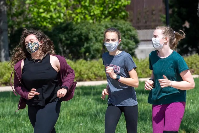 A group of women run while wearing a face masks.