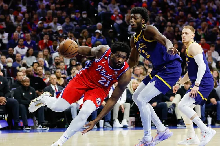 Sixers center Joel Embiid attempts to drive past Golden State Warriors center James Wiseman and guard Donte DiVincenzo during the first quarter on Friday. Embiid had 34 points and 13 rebounds.