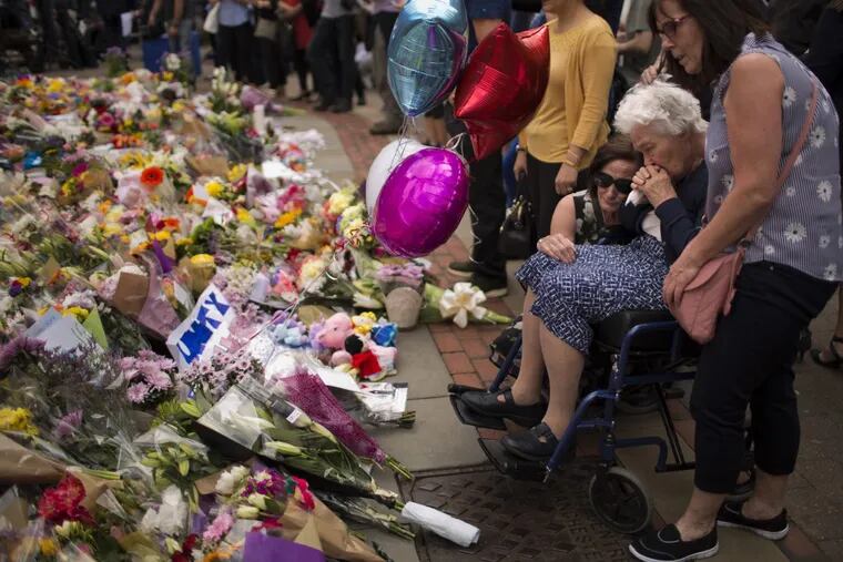 Women cry after placing flowers in a square in central Manchester after the deadly suicide attack outside an Ariana Grande concert on Monday)