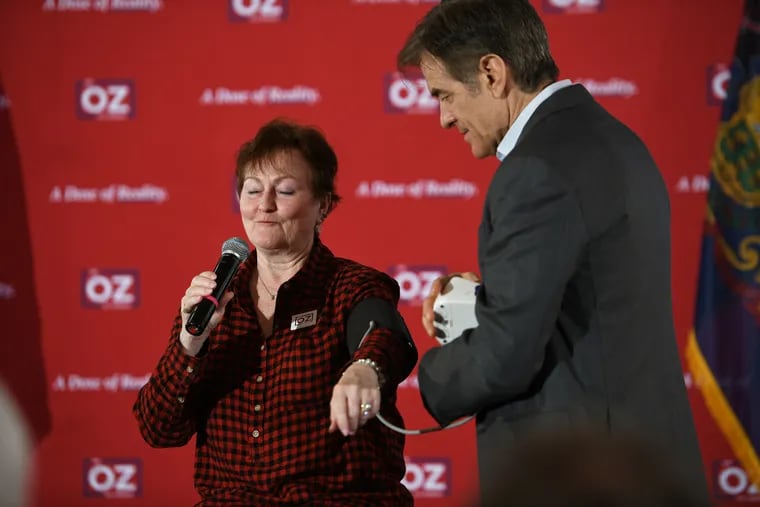Mehmet Oz, a Republican Senate candidate in Pennsylvania, takes the blood pressure of Joy Cahaley during a campaign town hall Thursday in West Chester.