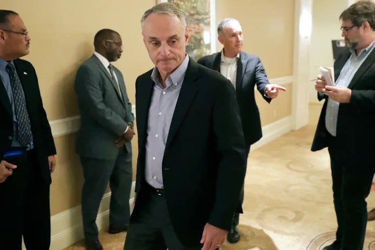 MLB Commissioner Rob Manfred, center, leaves a press conference during MLB baseball owners meetings, Thursday, Feb. 6, 2020, in Orlando, Fla. (AP Photo/John Raoux)