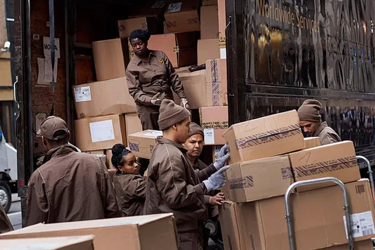 United Parcel Service Inc. (UPS) workers load boxes onto dollies for delivery in New York, U.S., on Wednesday, Nov. 12, 2014. UPS plans to spend $175 million on improving its operations during the holiday rush. It's opening 14 temporary shipping facilities to help expedite deliveries, upgrading its Orion software to plot the best route for drivers, and is hiring as many as 95,000 seasonal workers to field packages. Photographer: Michael Nagle/Bloomberg