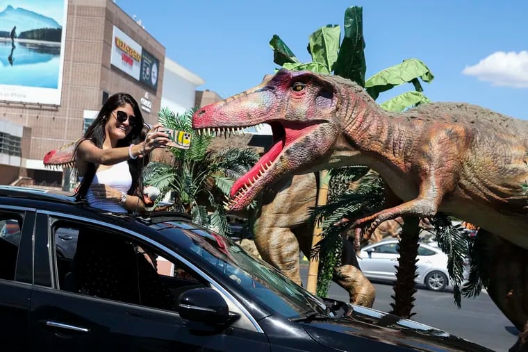 Karla DeJesus and her daughter Alejandra Rosario, 5, both of Delran, N.J., pose for a selfie at Jurassic Quest in the parking lot of the Wells Fargo Center in Philadelphia on Sunday. COVID-19 forced the interactive show to convert to a drive-through experience.