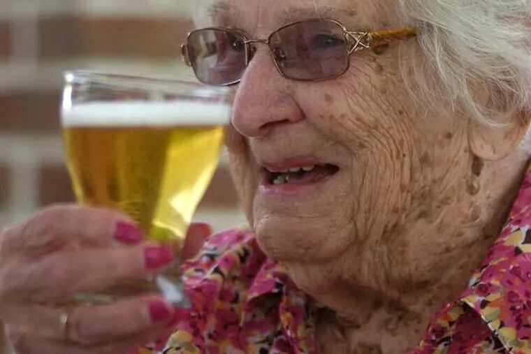 Pauline Spagnola , 100, hoists a beer at Golden Living Center in Luzerne County last week. Brewers have joined a coalition supporting new water protections. (MARK MORAN / The [Wilkes-Barre] Citizens' Voice)