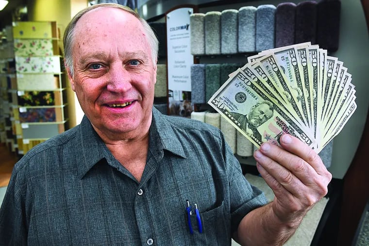 Kirk Bower holds up a stack of $50 bills inside Kissingers Floor & Wall on Front Street in Berwick. Keith Kaupt/Press Enterprise