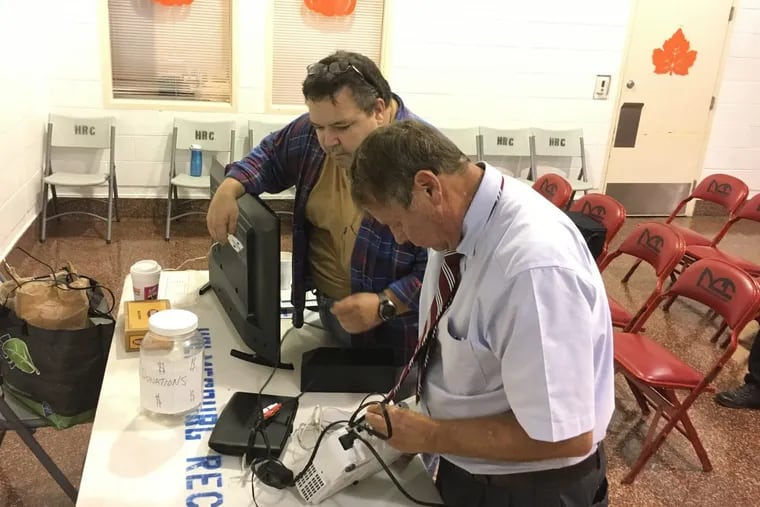 John Birch Society chapter leader Chris Affleck (left) works on fixing a TV monitor with field coordinator Kip Webster at the Holmesburg Recreation Center on Tuesday, Sept. 19, 2017.