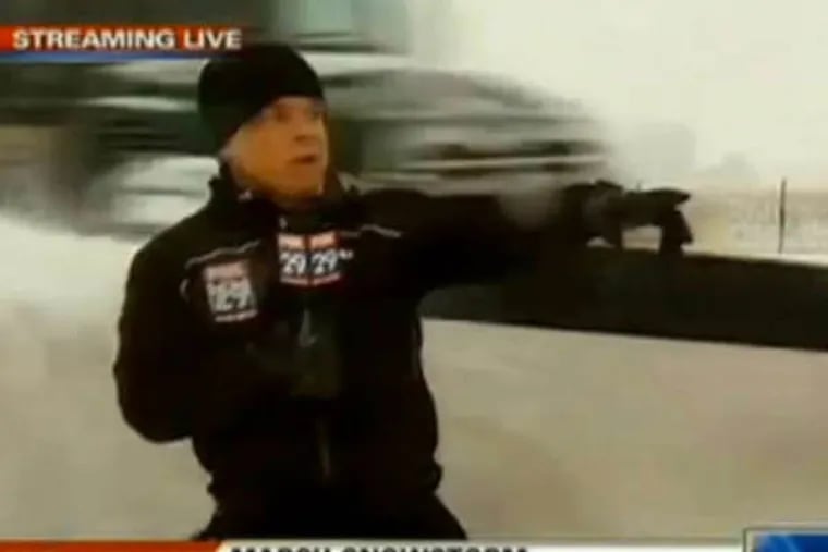 Fox 29's Steve Keeley points down the road right before getting walloped with snow from a plow.