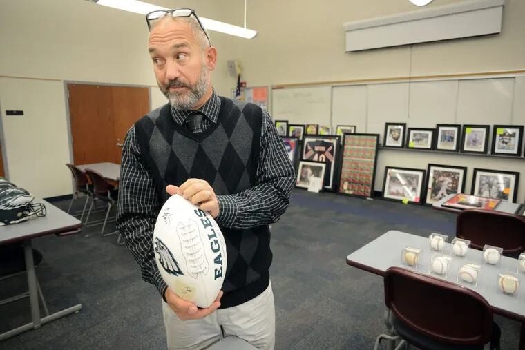 Auctioneer Alfred Finocchiaro holds up a football signed by a Philadelphia Eagles player during the online auction of some sports memorabilia, most of which came from a Cherry Hill con artist.