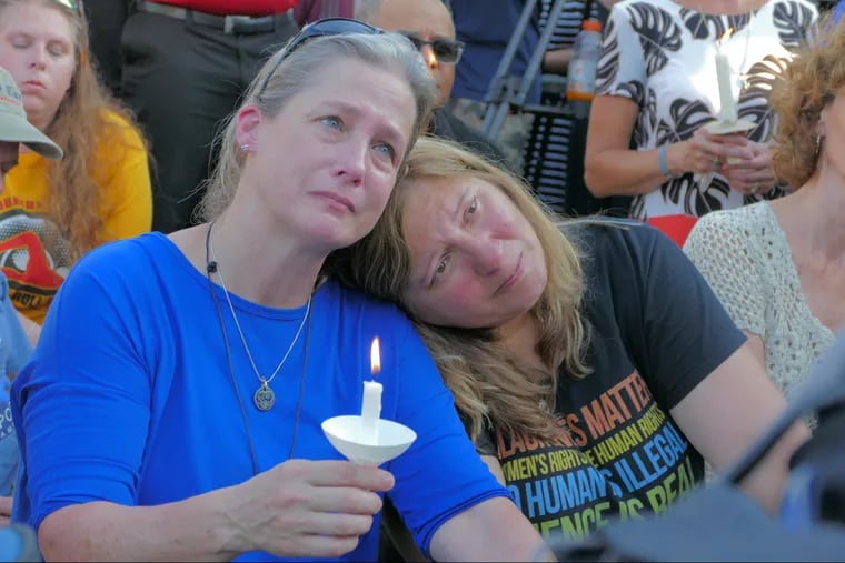Yasemin Jamison rests her head on Carol Geithner's shoulder during a candlelight vigil on Friday at Annapolis Mall for the five Capital Gazette employees slain during a shooting spree in their newsroom.