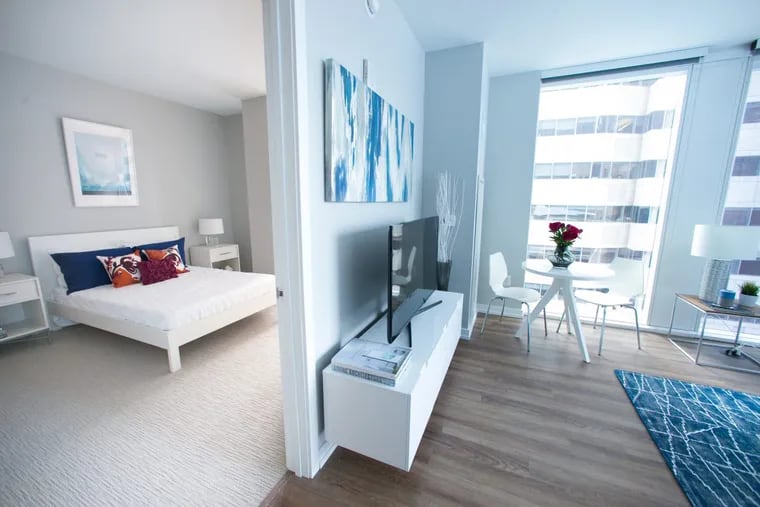 A bedroom and living room in a two-bedroom, two-bathroom luxury apartment at 1919 Market St. in Philadelphia.