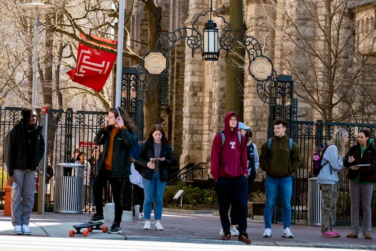 Students wait to cross Broad Street under the iron gate entrance to Polett Walk on the campus of Temple University.