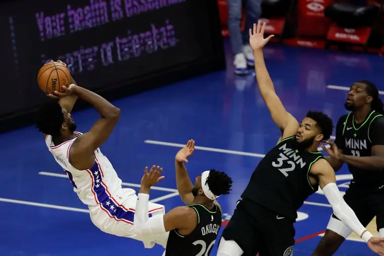 Sixers center Joel Embiid shoots the basketball falling back against Minnesota Timberwolves forward Josh Okogie, center Karl-Anthony Towns and center Naz Reid on Saturday, April 3, 2021 in Philadelphia.  Embiid made the basket and was fouled.