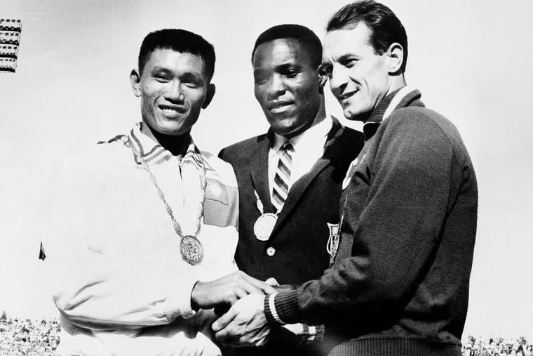 In this Sept. 7, 1960, photo, Rafer Johnson is flanked by runners-up Chuan-Kwang Yang, left, of Taiwan, and Vasily Kuznetsov of Russia, as they join in three-way handshake after receiving medals for the decathlon event of the Olympics in Rome, Italy.