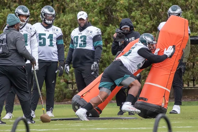 Eagle defensive end Brandon Graham, right, knocks down blocking dummies as the defense prepares for the Cowboys at Eagles practice at the NovaCare Complex on Thursday October 17, 2019.
