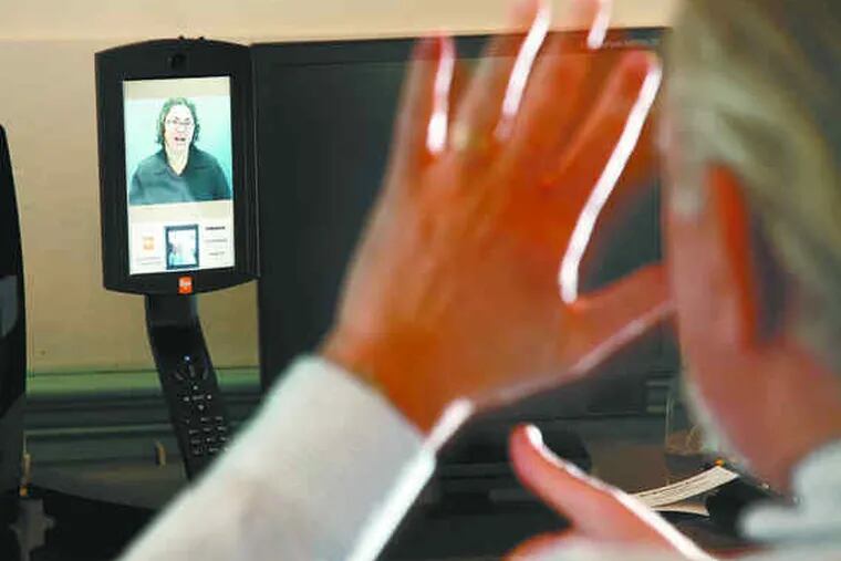 Larry Taub makes a phone call on a videophone, which allows users to communicate with a relay center through sign language.