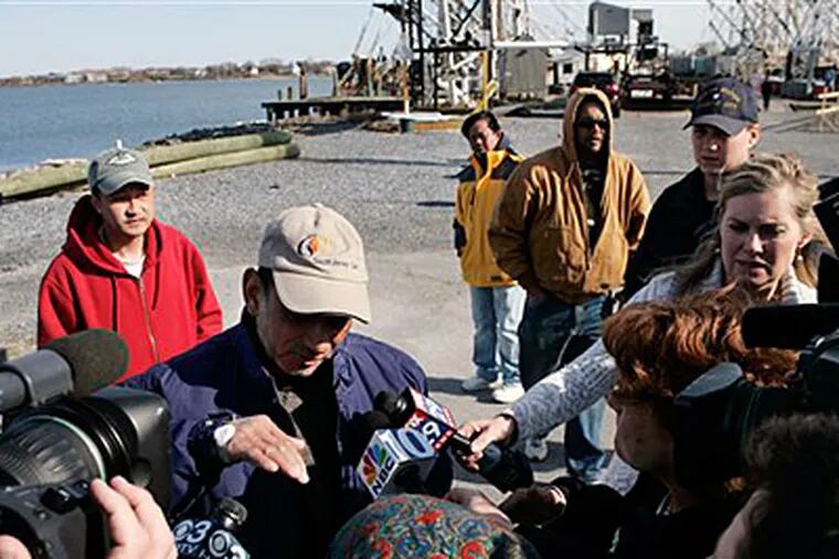 Fisherman Jose Arias, center, gestures with a bandaged hand, as he stands near the Cold Spring Fish & Suppy docks in Cape May on Tuesday and tries to describe how the fishing boat The Lady Mary sank earlier Tuesday. (AP Photo/Mel Evans)