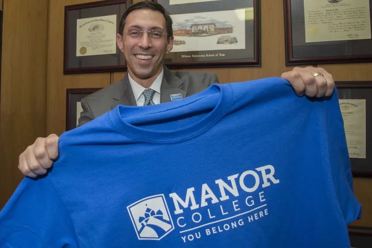 Manor College President Jonathan Peri, 43, displays new school logo and slogan on a t-shirt in his office Friday, Jan. 27.