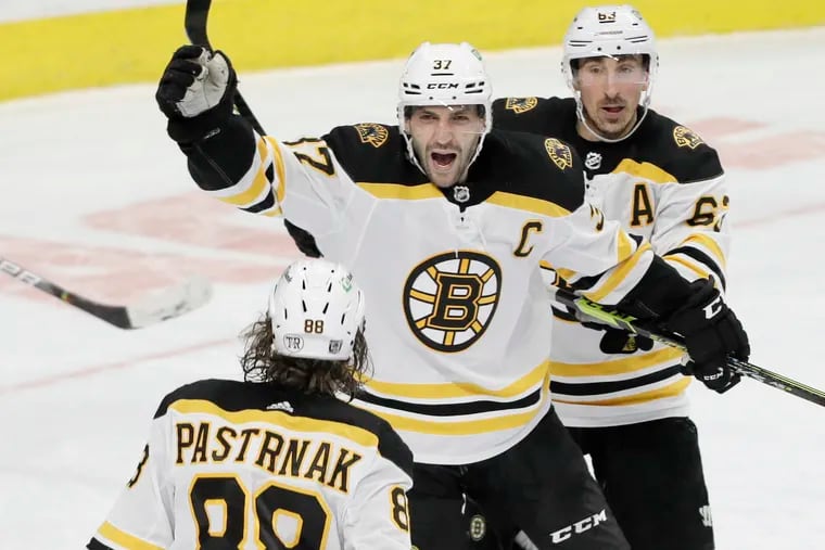 Bruins David Pastrnak, Patrice Bergeron(37) and Brad Marchand (right) celebrate the overtime win over the Flyers.