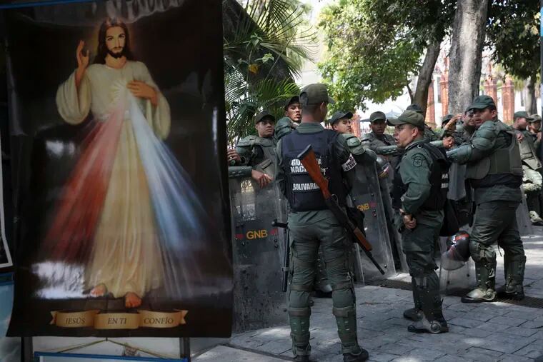 Venezuelan Bolivarian National Guardsmen line up near a Divine Mercy Jesus Christ poster outside the National Assembly in Caracas, Venezuela, Tuesday, Jan. 29, 2019.