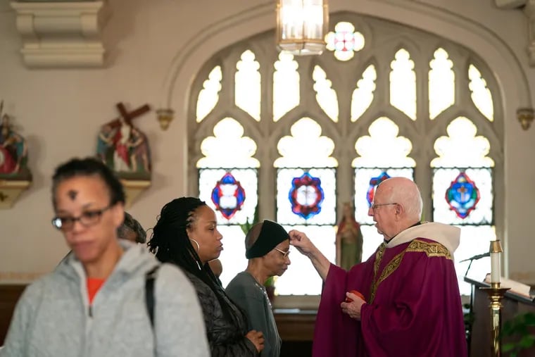 The Rev. Msgr. Wilfred J. Pashley puts ashes on a congregant's forehead at an Ash Wednesday service at St. Barbara Catholic Church in Wynnefield in this 2019 file photo. This year, Ash Wednesday and Valentine's Day fall on the same day.