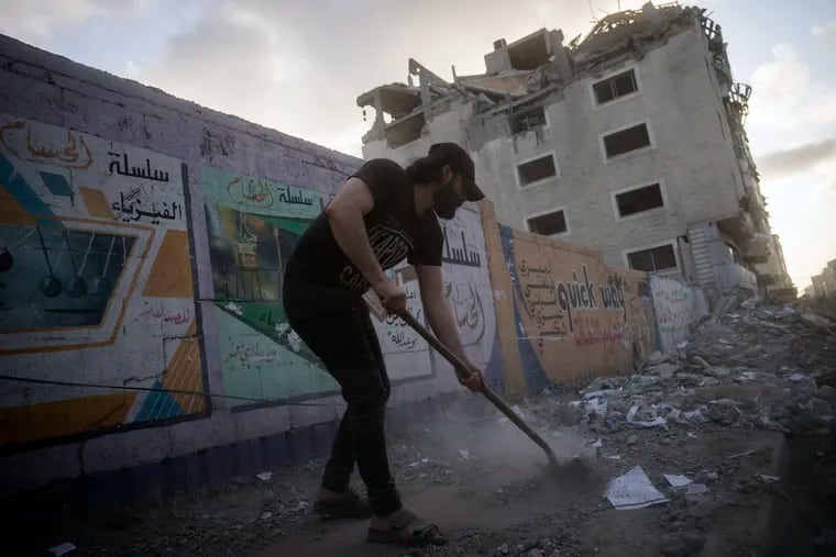 A man cleans the streets of debris on Friday beside a building that was damaged in an air-strike during 11-day war between Gaza's Hamas rulers and Israel.