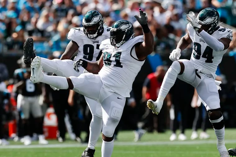 Kickin' it: Fletcher Cox celebrates between Josh Sweat (94) and Javon Hargave after his first sack of the season, against the Panthers on Sunday.