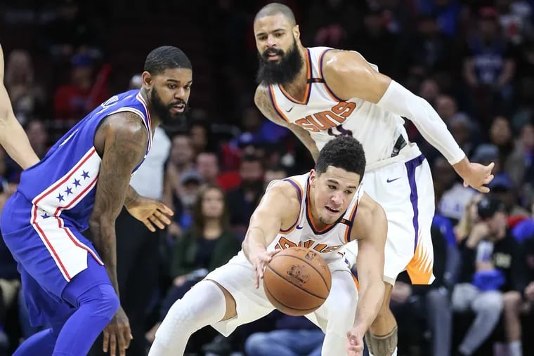 Suns’ guard Devin Booker grabs a loose ball as Tyson Chandler (right) and Sixers’ forward Amir Johnson watch during the fourth quarter.