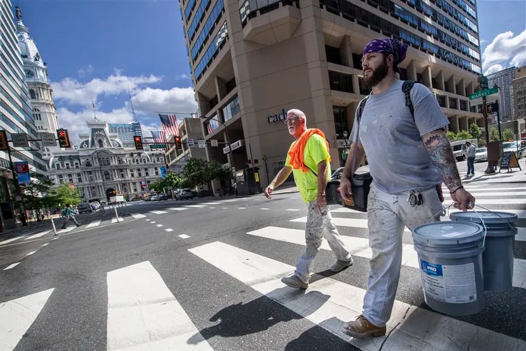 Construction workers walk along Market Street near Philadelphia City Hall in Philadelphia, Pa.