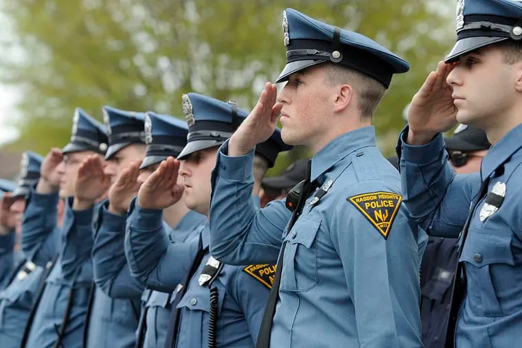 Haddon Heights police officers salute as the borough remembers the 20th anniversary of a 1995 shooting that left two officers dead and a third severely injured, on April 20, 2015. ( TOM GRALISH / Staff Photographer)