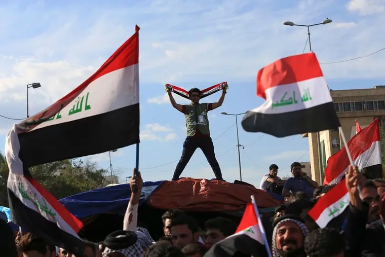 In this Thursday, March 31, 2016 file photo, followers of Shiite cleric Muqtada al-Sadr wave national flags as they end their sit-in outside the heavily guarded Green Zone in Baghdad.