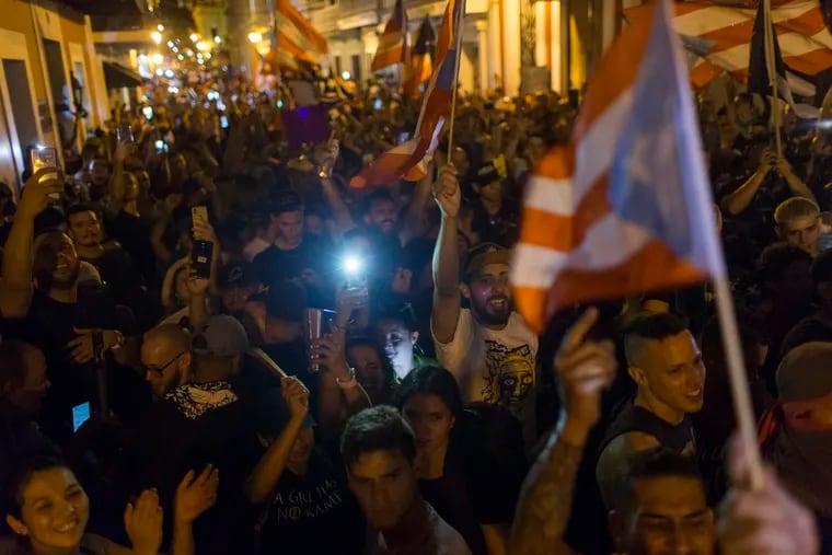 People celebrate outside the governor's mansion La Fortaleza, after Gov. Ricardo Rossello announced that he is resigning Aug. 2 after weeks of protests over leaked obscene, misogynistic online chats, in San Juan, Puerto Rico, Wednesday, July 24, 2019.