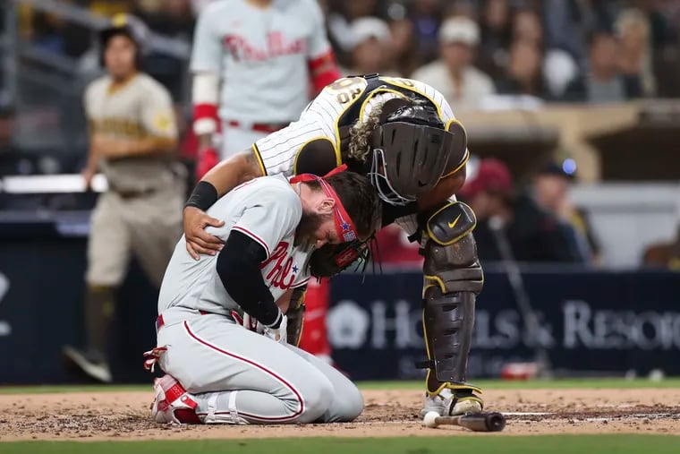 Philadelphia Phillies' Bryce Harper, bottom, reacts after being hit by a pitch from San Diego Padres' Blake Snell as Padres catcher Jorge Alfaro checks on him duirng the fourth inning of a baseball game Saturday, June 25, 2022, in San Diego.
