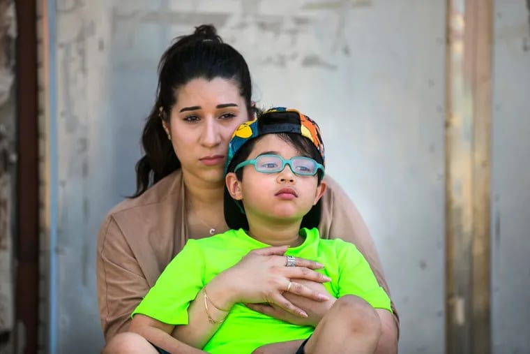 Cristine Gonzalez, back, holds her six-year-old son Dean Pagan, front, at a playground in Philadelphia. Dean was severely lead poisoned at Comly Elementary School.