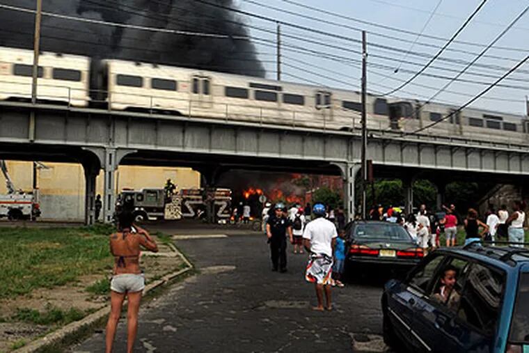 PATCO highspeed line train passes fire scene in South Camden on Thursday, June. 9, 2011, as neighborhood residents come out to watch firefighers. (Tom Gralish / Staff Photographer)
