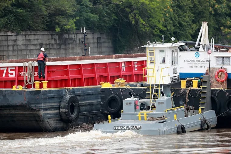A tugboat pushes the barge that was stuck under the Vine Street Expressway in Philadelphia on Thursday.