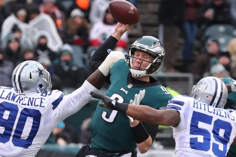 Eagles quarterback Nick Foles is hit while throwing the ball by Dallas’ DeMarcus Lawrence (90) and pressured by Anthony Hitchens (59) in the first quarter of Sunday’s 6-0 loss to the Cowboys.