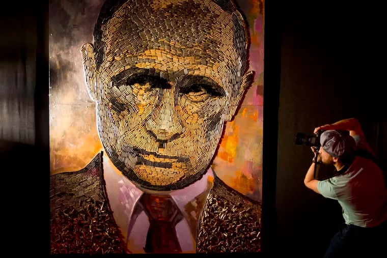 A photographer shoots a painting called &quot;The Face of War,&quot; by Ukrainian artist Dasha Marchenko, at a gallery in Kiev on Tuesday. The portrait of Vladimir Putin was made of 5,000 cartridge cases used in the conflict in Ukraine. EFREM LUKATSKY / Associated Press